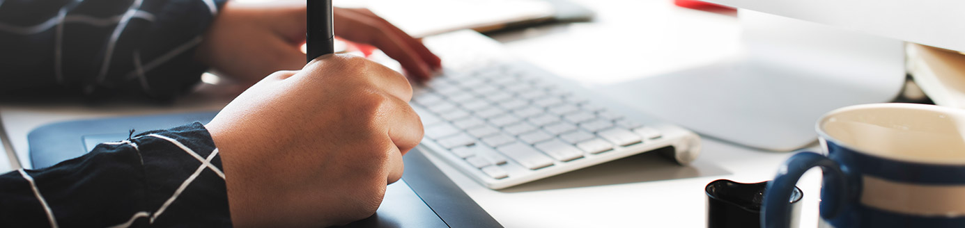 mãos manipulando um teclado e uma caneta de desenho digital